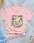 Pink t-shirt with 'Salty Moms' graphic design on a light blue surface with accessories.