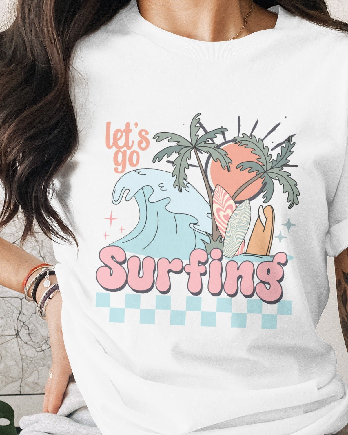 Person wearing a white t-shirt with a surfing design and text.