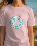 Person wearing a pink t-shirt with a tropical design on a beach