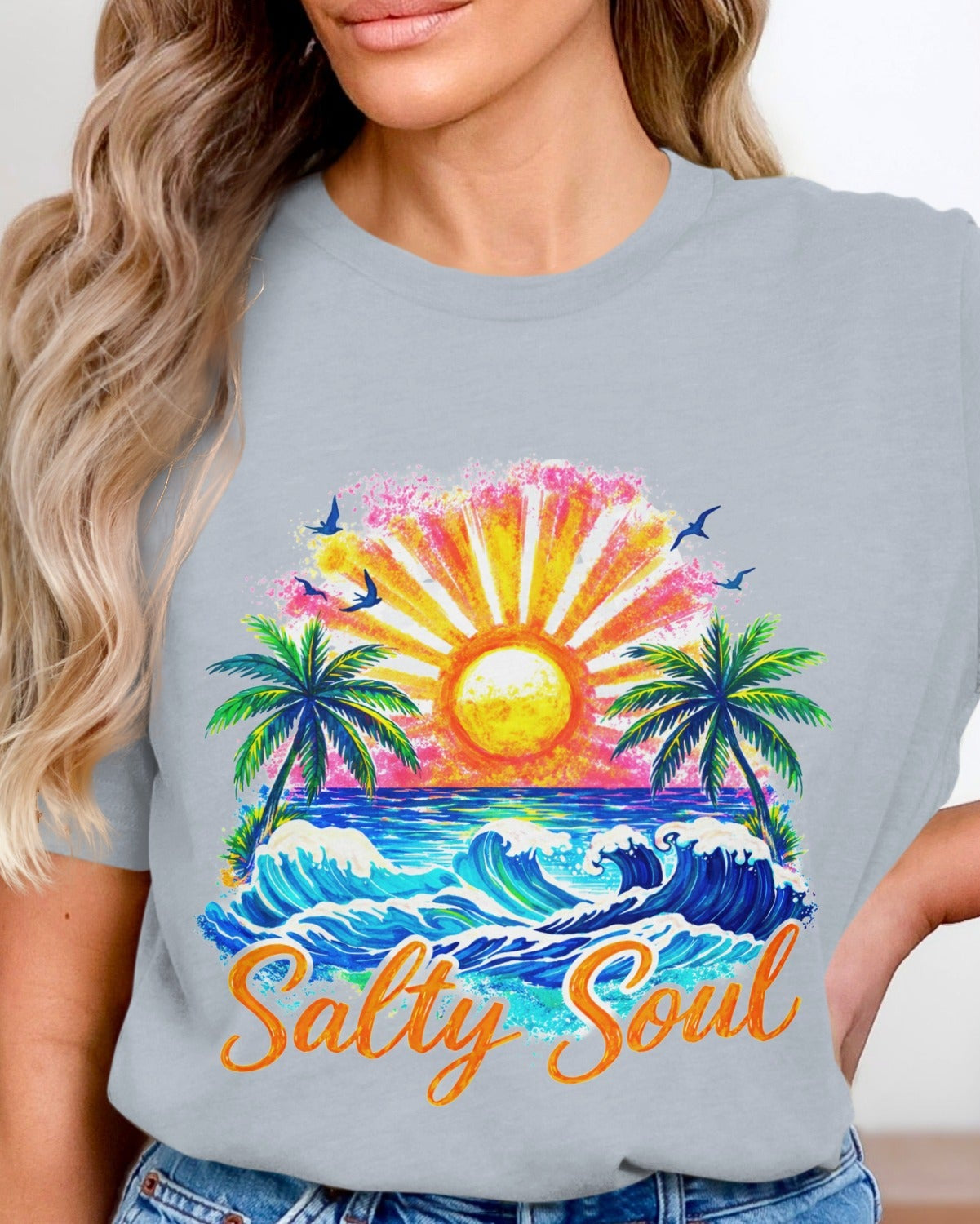 Person wearing a t-shirt with a colorful design of a sunset, palm trees, and the text 'Salty Soul'.