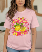 Person wearing a pink t-shirt with a lemon graphic and text in a living room.