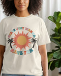 Person wearing a t-shirt with a colorful graphic design featuring a sun and palm trees.