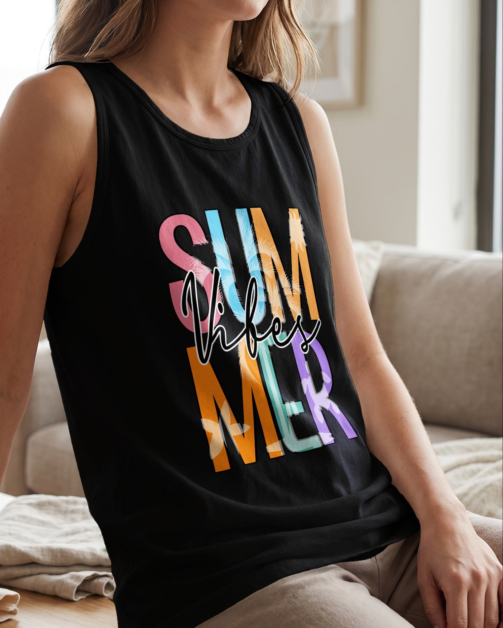 Person wearing a black tank top with colorful text sitting on a couch.