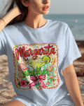 Person wearing a t-shirt with 'Margarita Weather' design on a beach.