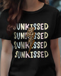 Person wearing a black t-shirt with 'SUNKISSED' text and a leopard print design on a street background.