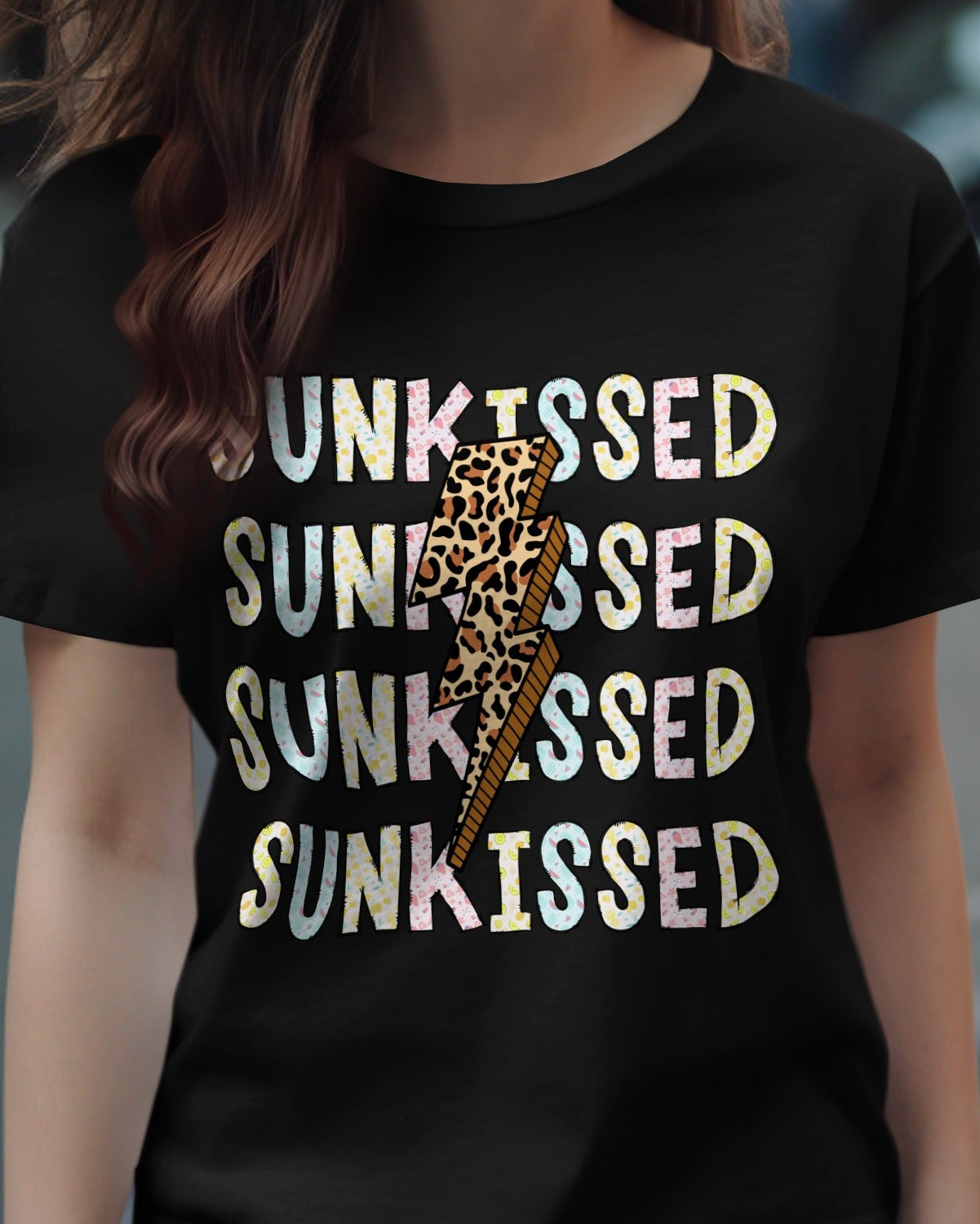 Person wearing a black t-shirt with 'SUNKISSED' text and a leopard print design on a street background.