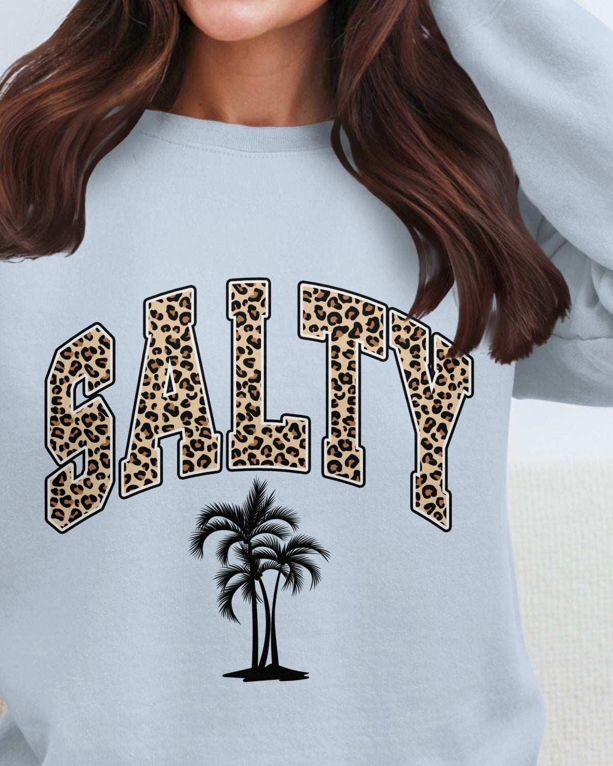 Light blue sweatshirt with 'SALTY' in leopard print and a palm tree on a plain background