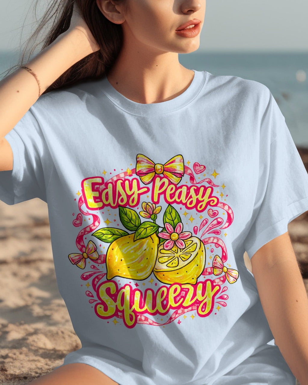 Woman wearing a t-shirt with a lemon graphic and text on a beach.
