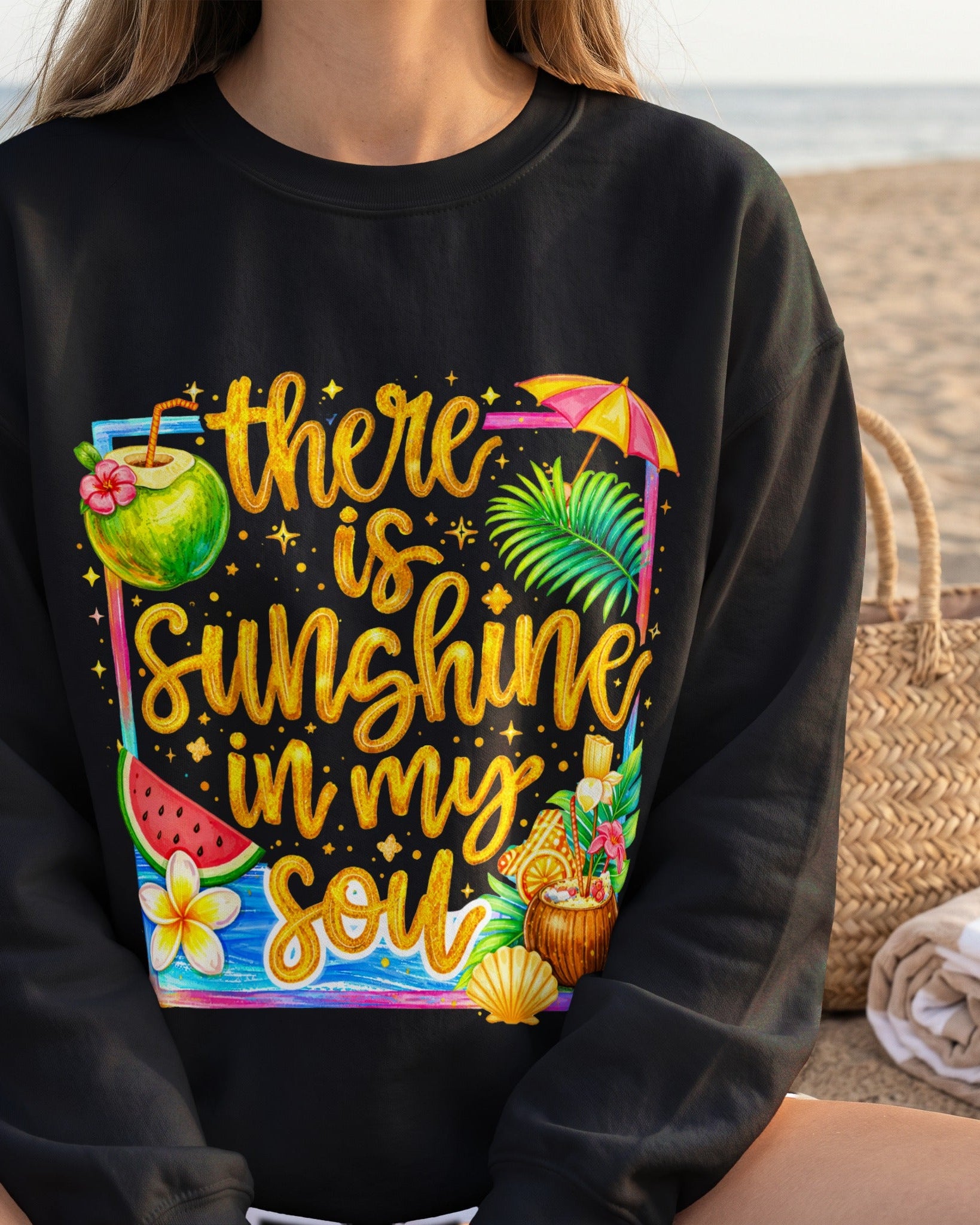Black sweatshirt with tropical design and text 'there is sunshine in my soul' on a beach.
